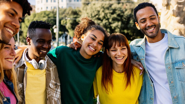 Happy diverse group of millennial students and best friends enjoying time together outdoors on a sunny day, laughing and bonding at the city street. Youth, friendship, and positive lifestyle concept.