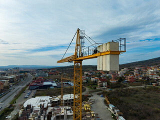 Construction site with crane overlooking city landscape and buildings during daytime with clouds in the sky