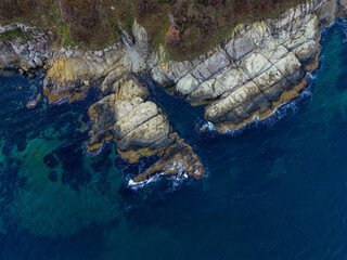 Rocky coastline with waves crashing against cliffs in a natural setting near the ocean during...