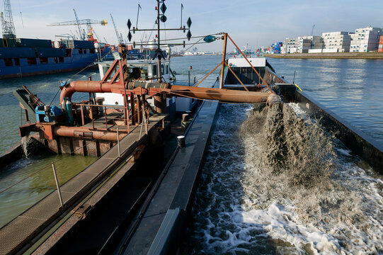 Industrial dredging barge with crane and navigation signals working in harbor