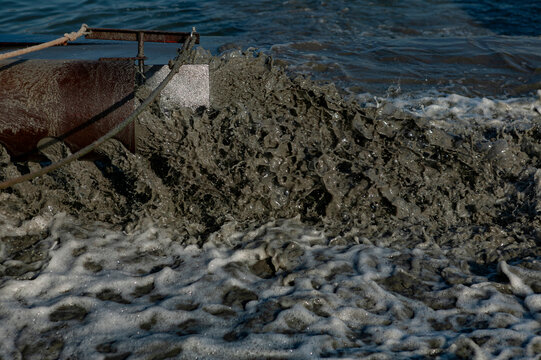 Close-up of liquified sand and sediment being pumped with foamy discharge