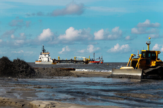 Bulldozer and dredging vessel working on beach nourishment project
