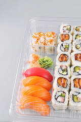 Assorted sushi rolls and nigiri in clear plastic takeout tray