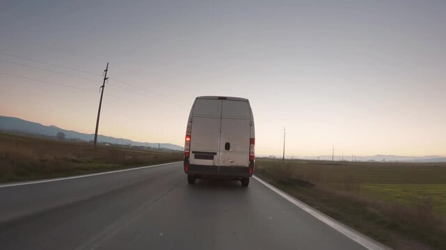 Suspicious van make crime transportation of illegal goods on rural road at sunset. Vehicle drive without plate numbers to protect from police identification