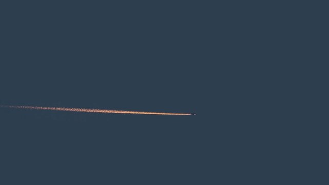 Trails from passenger commercial airplane flying at sunset,sunrise, chemtrails conspiracy theory concept