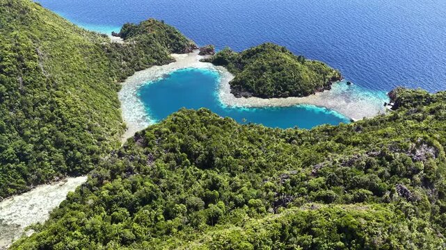 Rock islands, composed of ancient, uplifted reefs, surround a heart-shaped lagoon in Misool, Indonesia. This region harbors spectacular marine biodiversity and is a popular destination for diving.