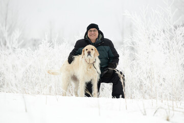 winter portrait of man with his dog out in the snow