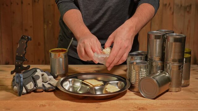Man survivor preparing meal from old canned food, survival escape in forest wooden cabin from city. War, economic policies and climate change disasters consequences. Starvation and housing crisis.
