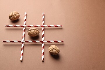 Tic tac toe game made with walnuts on beige background. Space for text