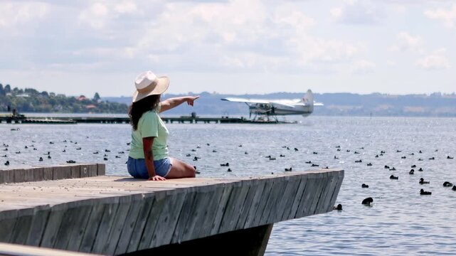 Woman on a pier pointing at a seaplane in New Zealand