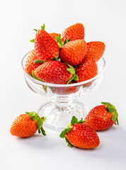 Strawberries in a glass bowl, placed individually on a white background.