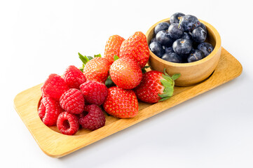 Appetizing variety of forest fruits (strawberries, strawberries, raspberries, blueberries, red berries) on a wooden tray and mint leaves