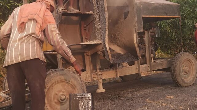 Workers using a machine to mix asphalt, Close up of a Bitumen Mixing Machine OR Asphalt Mixer, it is widely used in India and road construction contexts.