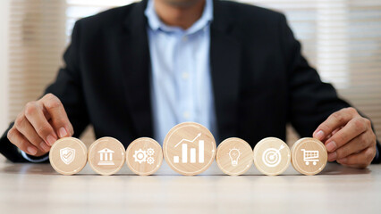 Hand chooses wooden toy stack with graph and business strategy icon for target goal to growth and financial marketing analysis or human resource management and investment concepts.