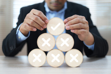 Hand choose check mark with cross symbol on wooden toy stack for true or false changing mindset or way of adapting to change leader and transform quiz answer and poll concept.