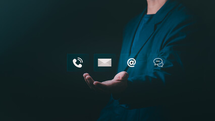 Businessman's hand presenting virtual contact icons for email, phone, address, and chat, Concept for customer support, communication technology, omnichannel marketing, and business connection.