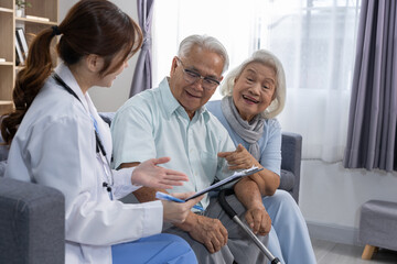 Obraz premium Friendly young female doctor consulting elderly couple sitting on sofa at home explaining health result with happy expression showing professional care support and medical assistance