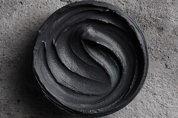 Black charcoal cosmetic mask texture swirling in jar