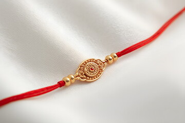 Traditional Gold Rakhi Bracelet on White Silk for Raksha Bandhan Festival