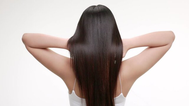 Slow motion rear view of young Asian girl shakes long straight hair. Female model is fluttering hair.