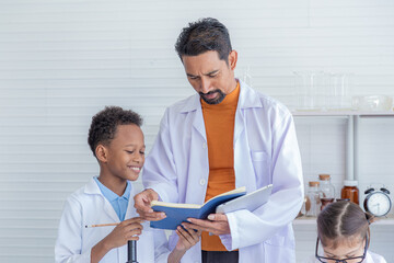 Fototapeta premium Group of multicultural students in lab coat uniform studying with Indian teacher writing report in laboratory, pupils boy and girls scientist having fun in science class with microscope and test tube