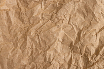 Fototapeta premium Crumpled brown kraft paper texture background, wrinkled recycled paper sheet,Top view of brown crumpled kraft paper texture background. A high-resolution close-up of wrinkled recycled paper sheet.