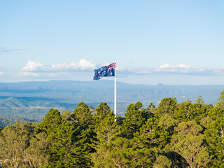 Scenic elevated views of the Australia flag on display at the Picnic Point public park area in Toowoomba with Table Top Mountain and the Bushland Reserve in the background, Queensland, Australia