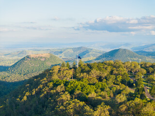 Scenic elevated views of the Australia flag on display at the Picnic Point public park area in Toowoomba with Table Top Mountain and the Bushland Reserve in the background, Queensland, Australia
