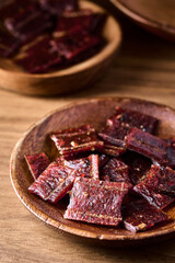 closeup pile of jerky pork in bowl on wood vertical background with copy space