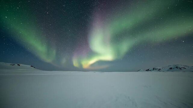 Nighttime landscape of the aurora borealis glowing green and purple across a starry sky above a snowy field and mountain range.