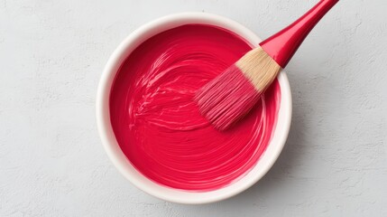 A vibrant red paint swirls in a bowl, with a brush resting inside, ready for creative projects.