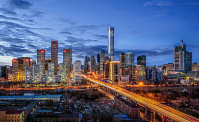 Fototapeta premium Modern Beijing CBD skyline with illuminated skyscrapers and traffic light trails at night, showing urban development, transportation and city life in China.