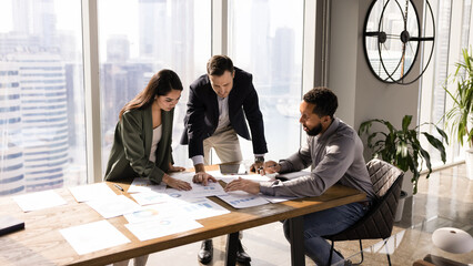 African American manager presenting project to investors, showing paper sales reports on meeting table, explaining marketing research results, discussing business plan. Banner shot