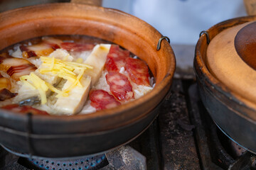 angle view clay pot rice of dried fish and Chinese sausage and vegetable being cooked at horizontal composition