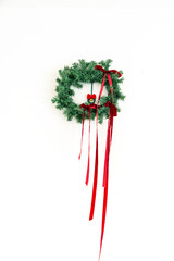 A minimalist Christmas wreath hangs on a clean white wall, with plenty of negative space, emphasizing seasonal warmth.