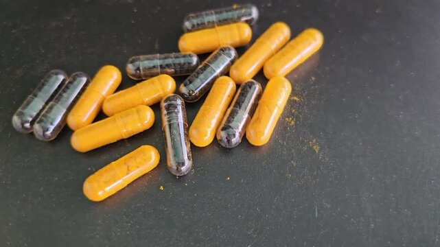 Capsules of herbs and supplements on a dark surface during the day highlighting nutrition and health choices