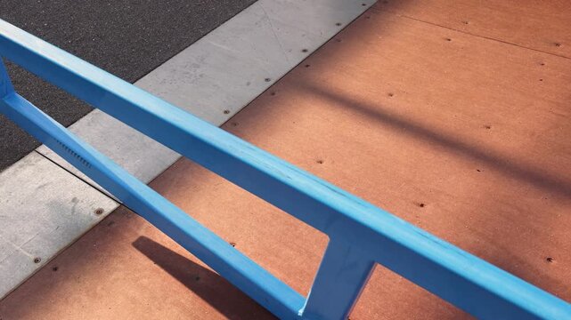 Metal rail installed on sloped ramp in skatepark designed for grinds and slides used in skateboarding aggressive inline skating and scooter riding urban sports equipment park detail