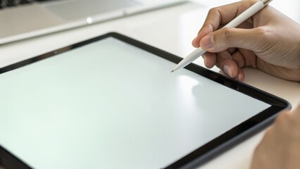 A person uses a stylus on a blank tablet screen, emphasizing digital art or design work in a modern workspace.