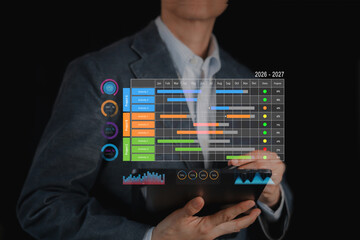 Businessman analyzing 2026-2027 project management schedule on tablet. Future corporate strategy planning with digital Gantt chart timeline, data analysis and business growth concept.