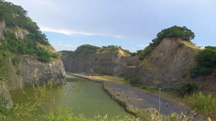 Fototapeta premium Scenic landscape of a lake surrounded by steep rocky cliffs and green hills.