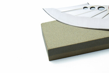 Stainless steel knife blade on a whetstone poised for sharpening, close-up studio shot emphasizing edge, texture, and reflection