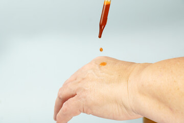 Hand applying an orange essential oil or serum using a dropper for skincare, health, and natural beauty treatment