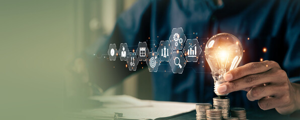 Businessman's hand chooses light bulb or lamp with bright and business icons for human resources or leadership and creativity thinking idea motivation or vision and knowledge learning. © Jintana