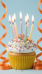 birthday cupcake with lit candles and sprinkles on blue background with orange ribbon streamers, festive party dessert, celebration concept with copy space