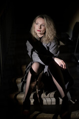 A stylish woman in a coat sits on the stairs. Noir style