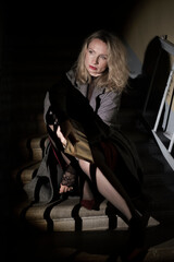 A stylish woman in a coat sits on the stairs. Noir style