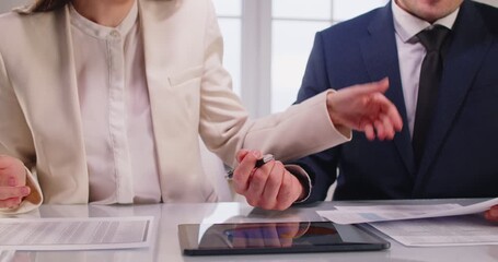 Business man in formal suit discussing with female colleague company finance growth analyzing data stat on tablet sitting at desk on workplace during a meeting in office. Teamwork concept. 4k video. - Powered by Adobe