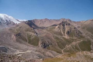 High-altitude mountain pass in the Trans-Ili Alatau range. Gravel road among Tuyuk-Su glaciers and rocky valleys, Tien Shan, Central Asia