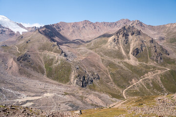 High-altitude mountain pass in the Trans-Ili Alatau range. Gravel road among Tuyuk-Su glaciers and rocky valleys, Tien Shan, Central Asia