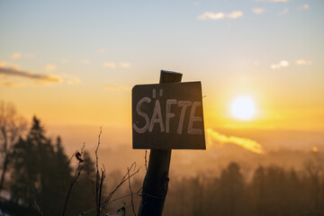 Selbstgeschriebenes Schild an einem Weinberg im Sonnenaufgang im Winter preist selbstgemachte, hausgemachte S&auml;fte an, Hofverkauf